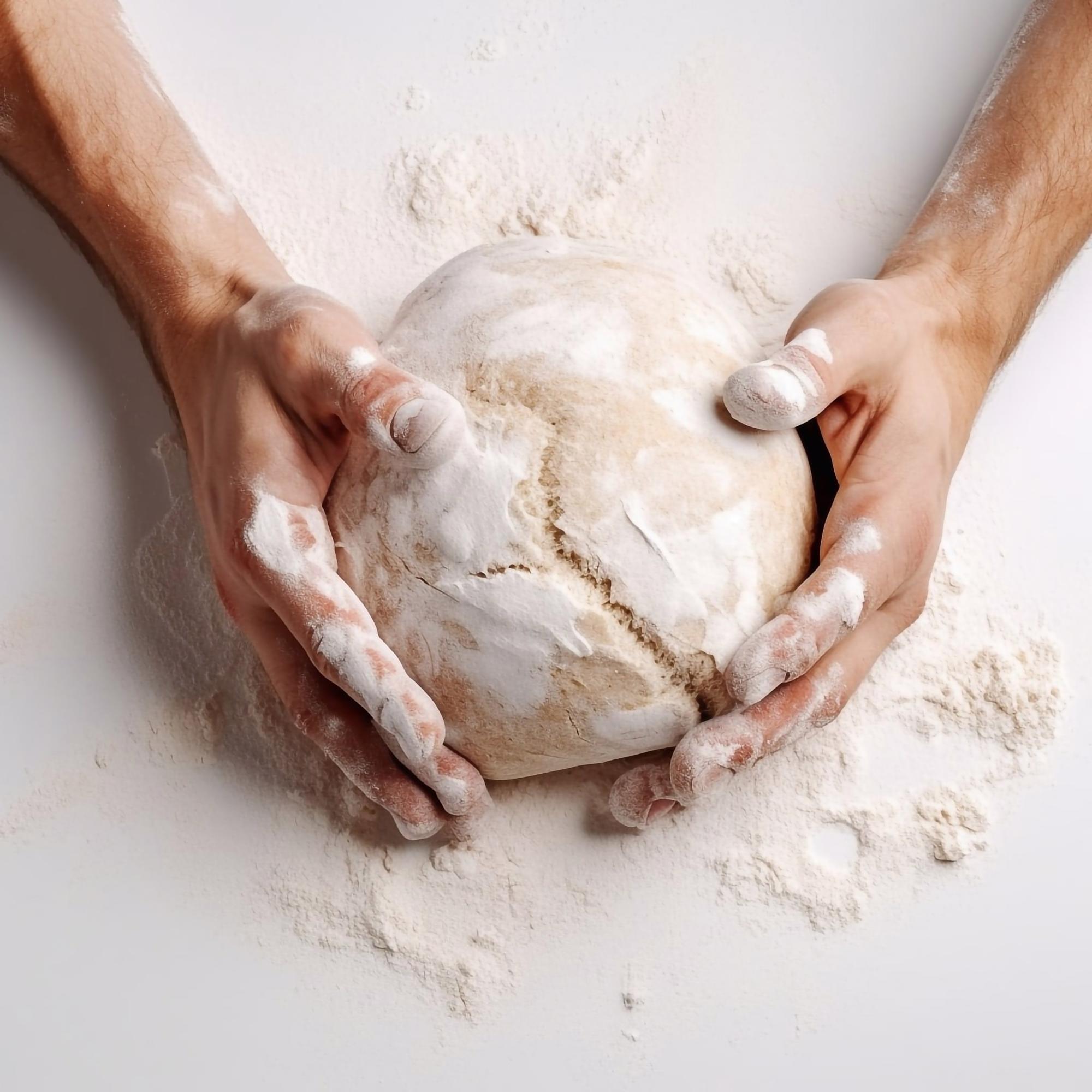Close-up of hands kneading dough in warm kitchen